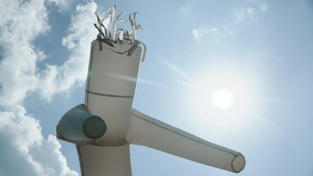 Funny air dancer actively moves against sunny sky, close-up. Crazy actor party goer energetically moves in wind, handheld action shot.