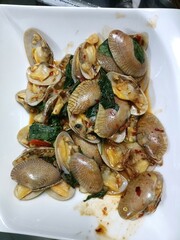 Stir fried clams with garlic and chili sauce in white plate
