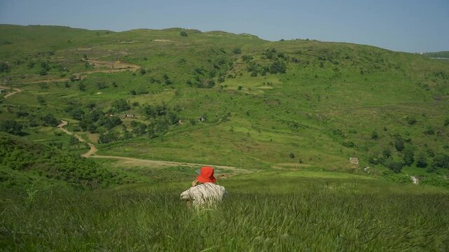 View of Rayta Hills in Udaipur, Rajasthan, India. Lush green mountains and a cloudy sky during the monsoon season. A perfect travel and holiday background, with a man sitting on the grass.
