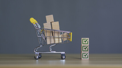 Shopping cart filled with wooden blocks and green checkmark badges representing quality assurance,...