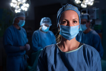 A focused medical professional stands ready in a dimly lit surgical room surrounded by a skilled team preparing for surgery