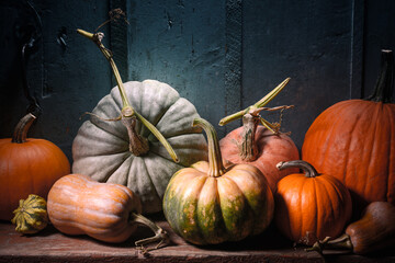Mixed pumpkins rest on wooden tabletop in rustic autumn arrangement. Seasonal decor scene for...