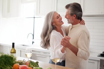 A joyful couple dances together in their kitchen surrounded by fresh produce and a bottle of wine enjoying a special moment