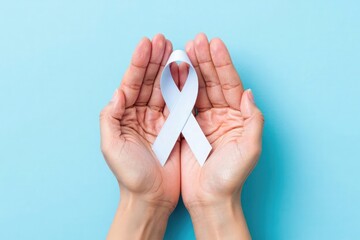 Hands cupping a light blue awareness ribbon on a solid blue background top view close up