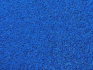 Vibrant blue rubber granule road surface in close-up, gritty texture perfect for sports track...