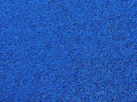 Vibrant blue rubber granule road surface in close-up, gritty texture perfect for sports track backgrounds