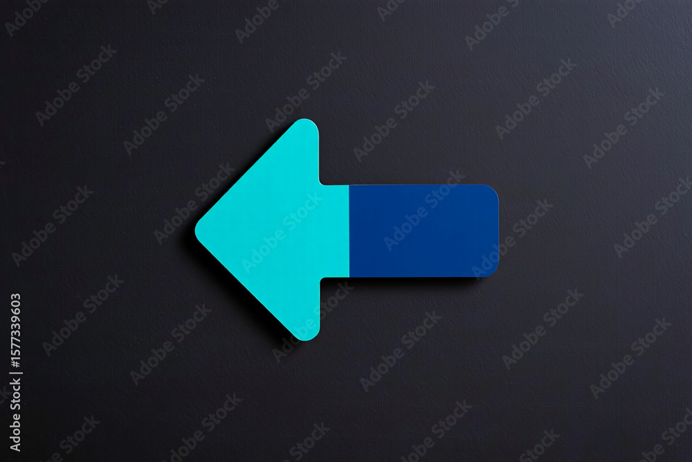 Poster a two toned arrow pointing left on a dark gray surface with a slight shadow