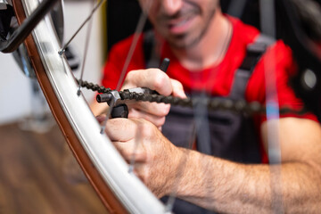 Portrait of professional caucasian serviceman repairing broken bicycle chain inside workshop.