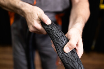 Professional serviceman holding external bicycle tire in workshop.
