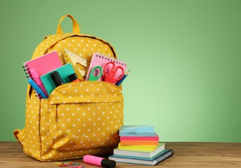 A yellow polka dot backpack is packed with school essentials ready for learning.
