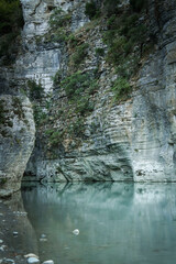 A stunning canyon with green-blue water flowing through gray rocky cliffs, creating a peaceful natural scene.
