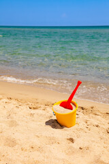 Colorful beach toys on sand near calm sea during sunny summer day