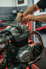 Mechanic repairing motorcycle engine with tools in workshop, close-up of hands and engine parts.