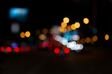 Blurred night traffic scene with glowing car lights and bokeh street lamps, creating a dreamy urban...