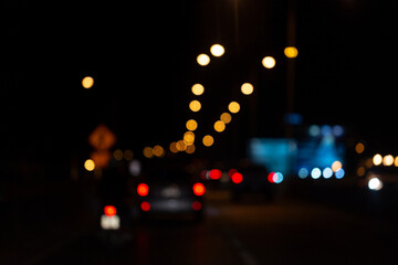 Blurred night traffic scene with glowing car lights and bokeh street lamps, creating a dreamy urban...