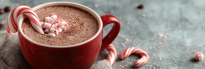 Rich hot chocolate with peppermint stick garnished in festive red cup during winter holiday season