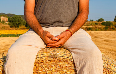 Parcial view of man resting of hay stack in peaceful farmland
