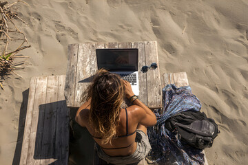Digital nomad working on beach, Symbolizes freedom, remote work, and the digital nomad lifestyle.
