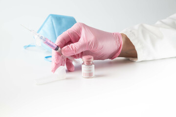 Breast cancer vaccine mock-up, pink vial, gloved hand holding syringe with pink fluid.  Women's...