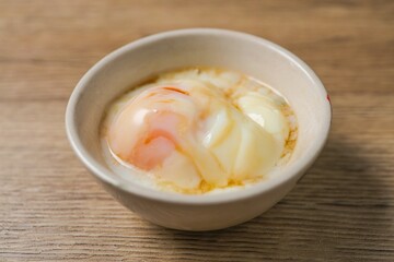 soft boiled egg, onsen egg in white bowl on wooden background	
