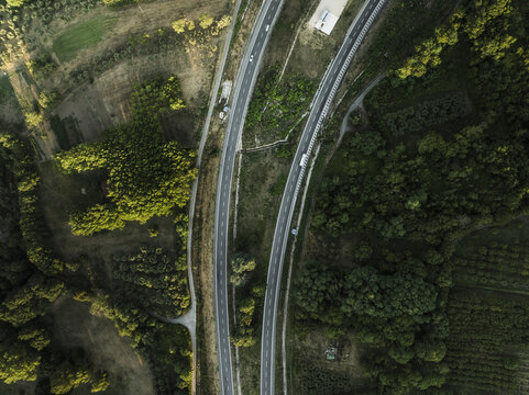 Aerial view of curving highways cutting through a vibrant landscape of lush green forests and cultivated fields, Montemiletto, Avellino, Italy.