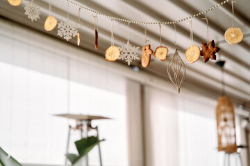 Festive winter garland with dried citrus and snowflake decorations hanging in cozy indoor setting