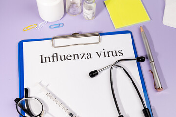 A Paper with “Influenza Virus” Title in Clipboard Set on the Desk with Stethoscope – Seasonal...
