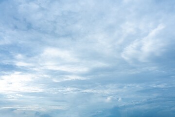 A wide expanse of light blue sky covered with layers of soft white and gray clouds