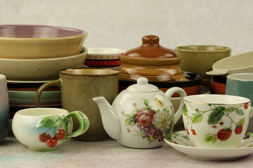 Lots of different dishes in the form of plates and mugs. Ceramic dishes of different colors for food. Plates and mugs are stacked.