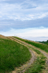 Rural flood embankment with dirt road and green fields under a summer sky