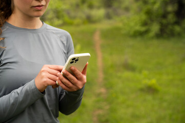 Young woman using GPS navigator app on phone in nature, female tourist trying to find a path during...