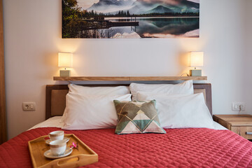 Cozy bedroom with red blanket interior decor features tranquil wall art and warm lighting