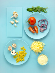 Creative food health diet concept photo of pasta dishes with vegetables on blue background.