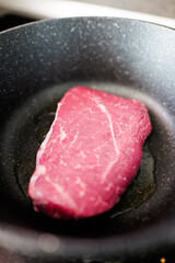 Juicy steak sizzling in a hot pan, showcasing its vibrant red color and marbling