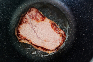 Sizzling beef steak cooking in a hot skillet with perfect sear marks