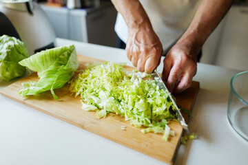 Chopping fresh lettuce for a vibrant salad in a cozy kitchen setting