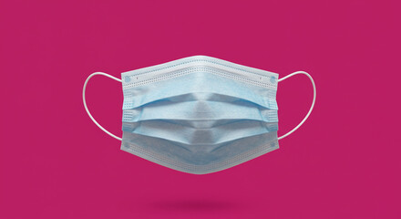 A blue disposable mask floating against a vibrant pink backdrop showcasing protection