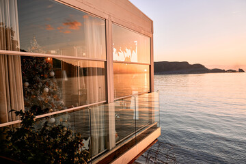Sunset reflections on modern glass house with sea view