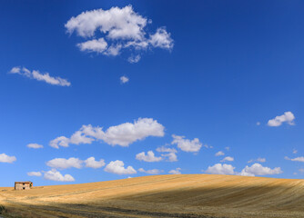 Summer hilly landscape with harvested fields in Apulia, Italy: abandoned farmhouses between light and shadow.