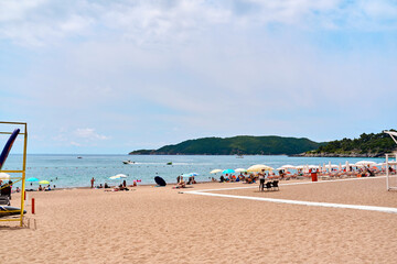 Scenic beach paradise with umbrellas and sunbathers on sandy coastline