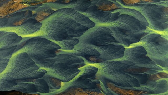 Aerial view of braided river channels carve through the landscape, creating a mesmerizing pattern of green and gold, Landmannalaugar, Iceland.
