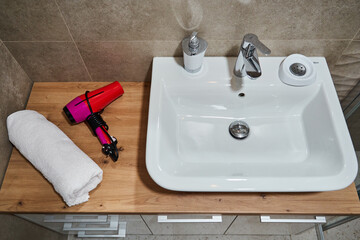 Bathroom counter with sink, hairdryer, and towel on wooden surface