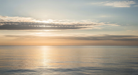 Fototapeta premium Sunlight breaks through clouds over the tranquil ocean at dawn