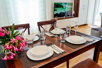 Elegant dining table setting in cozy modern living room with decorative plants and wooden furniture
