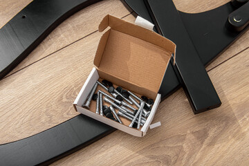 Wooden furniture parts and a box with fasteners and bolts. Furniture assembly kit