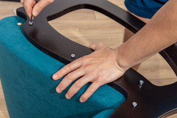 A man collects a chair. The key for tightening the bolts. Wooden furniture elements