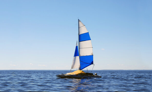 Sailing catamaran is a double-hulled vessel that uses the power of the wind to move, thanks to sails mounted on a mast. The catamaran is in a marching position and makes a long passage on the water.
