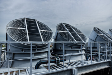 Cooling fans are installed on rooftop of large commercial building. Maintaining air circulation and temperature control. Tower air chiller HVAC.