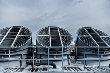 Cooling fans are installed on rooftop of large commercial building. Maintaining air circulation and temperature control. Tower air chiller HVAC.