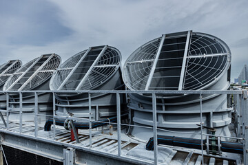 Cooling fans are installed on rooftop of large commercial building. Maintaining air circulation and temperature control. Tower air chiller HVAC.